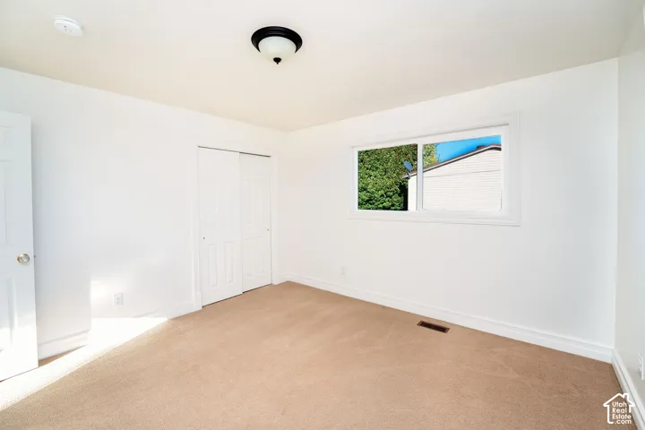 Neutral-toned wall-to-wall carpeting, sliding panel closet doors, and a double-pane sliding window
