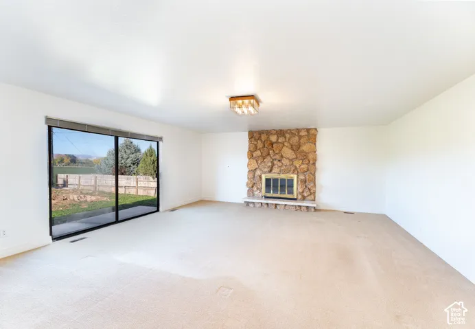 Floor-to-ceiling stone fireplace with a raised hearth, large sliding glass door, and flush-mount light fixture