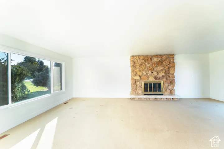 Floor-to-ceiling natural stone fireplace with a stone hearth and large windows providing natural light