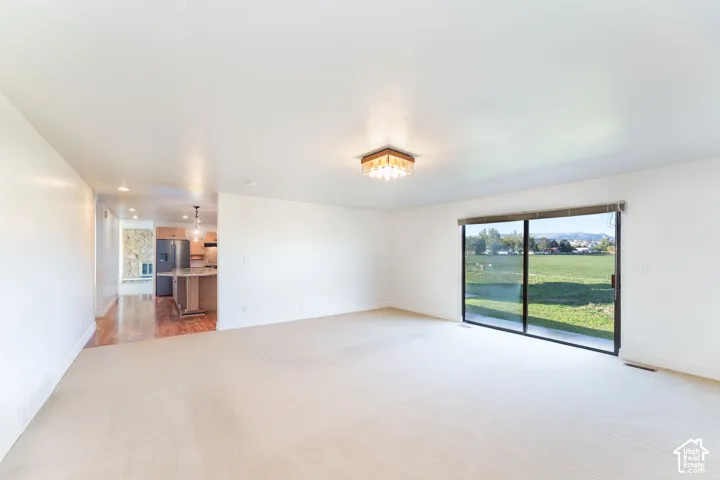 Living space featuring sliding glass doors, neutral wall-to-wall carpeting, and a flush-mount light fixture