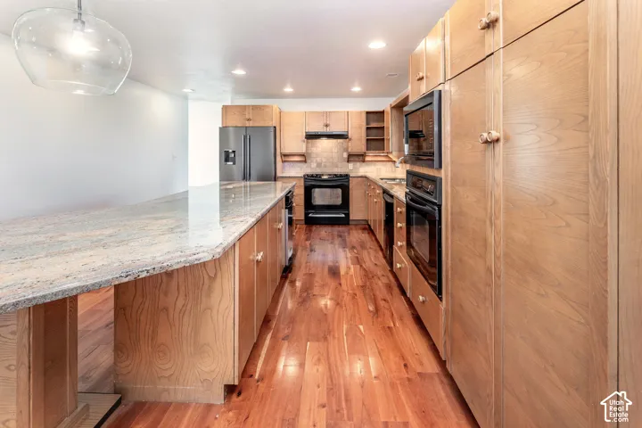 Kitchen featuring wood-finish cabinetry, stone countertops, wood-finish flooring, built-in wall ovens, and recessed lighting