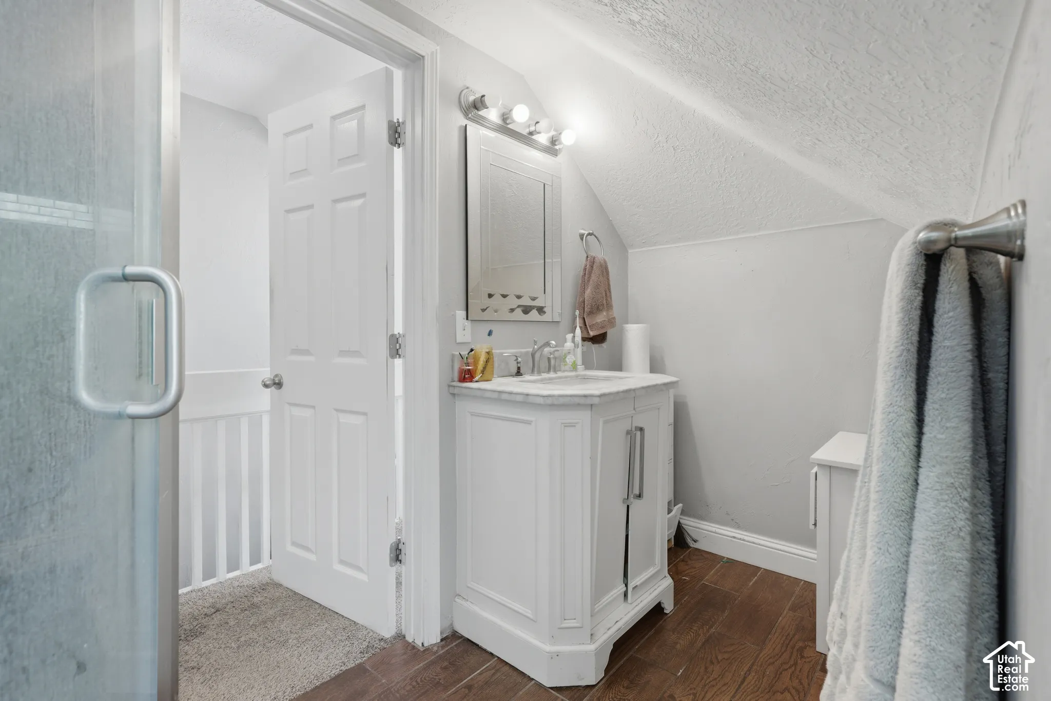 Bathroom featuring a vanity with stone countertop, drop-in sink, three-light vanity fixture, and wood-finish flooring