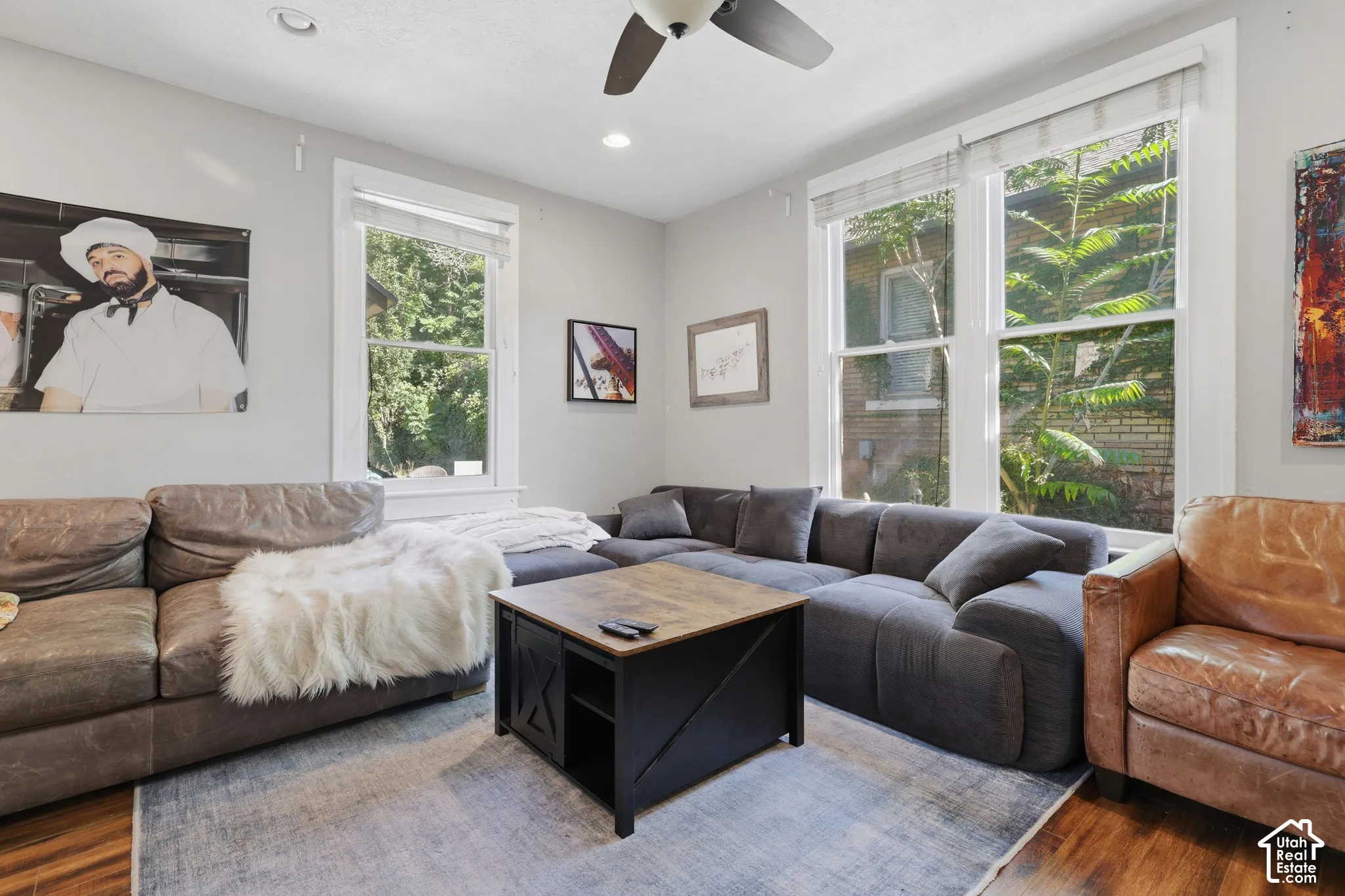 Neutral-toned room featuring wood-finish flooring, dual-pane windows with trim, and a ceiling fan