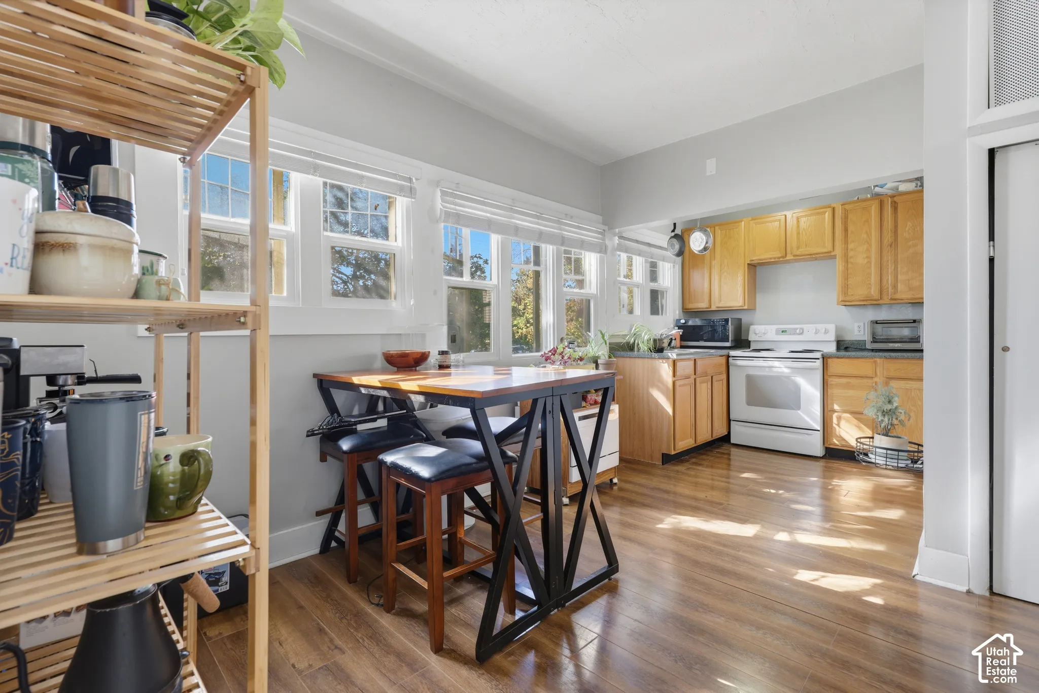 Kitchen featuring wood-finish cabinetry, natural wood-finish flooring, and multiple windows providing interior light