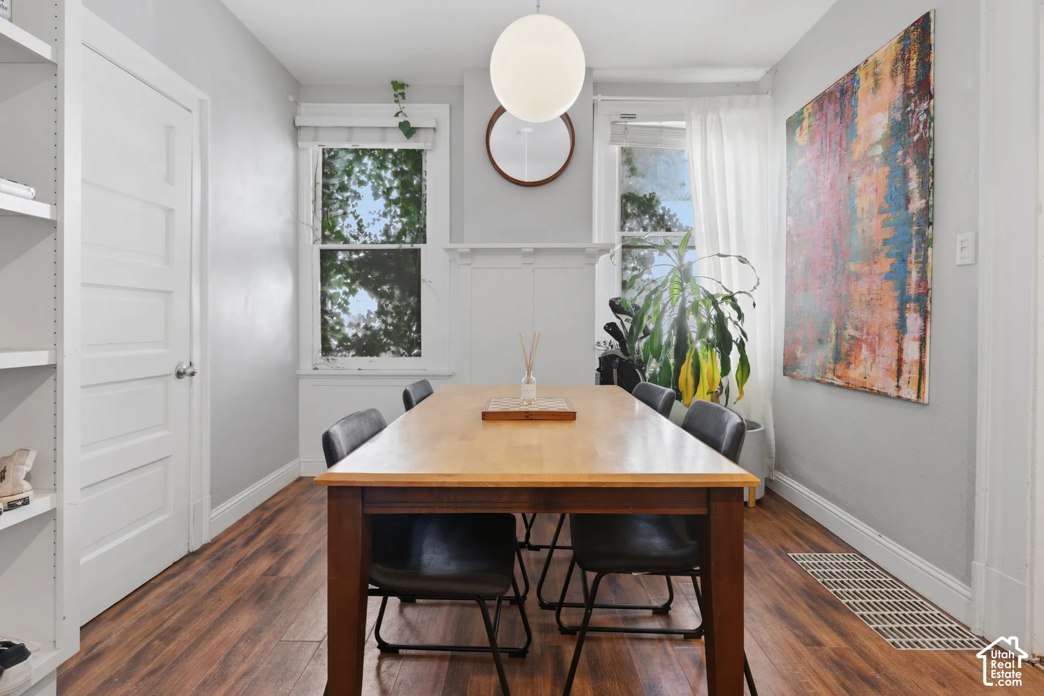 Wood-finish flooring, white built-in shelving, decorative fireplace mantel, globe pendant lighting, and oversized windows
