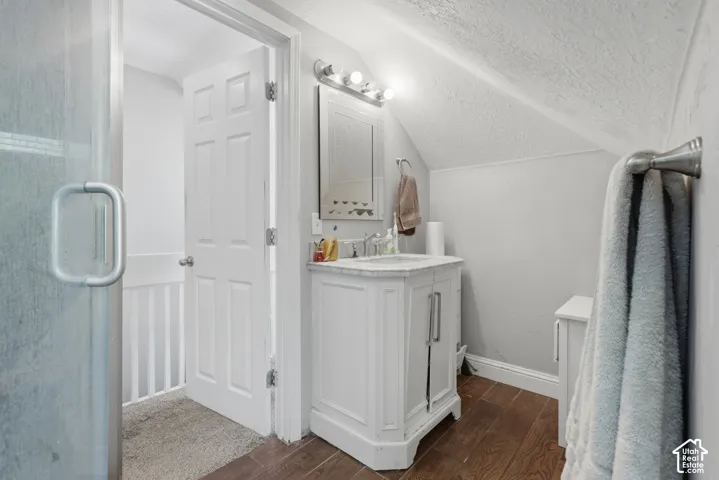 Bathroom featuring a vanity with stone countertop, drop-in sink, three-light vanity fixture, and wood-finish flooring