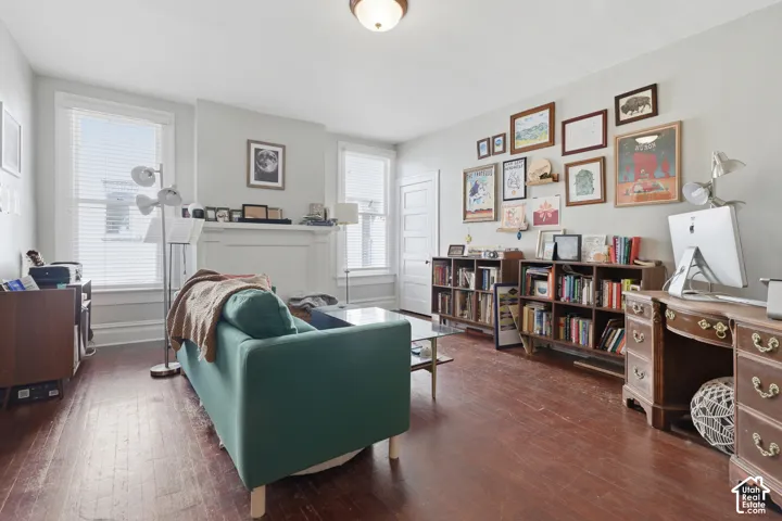 Interior space featuring wood-finish flooring, two large windows, a decorative fireplace mantle, and a multi-panel interior door