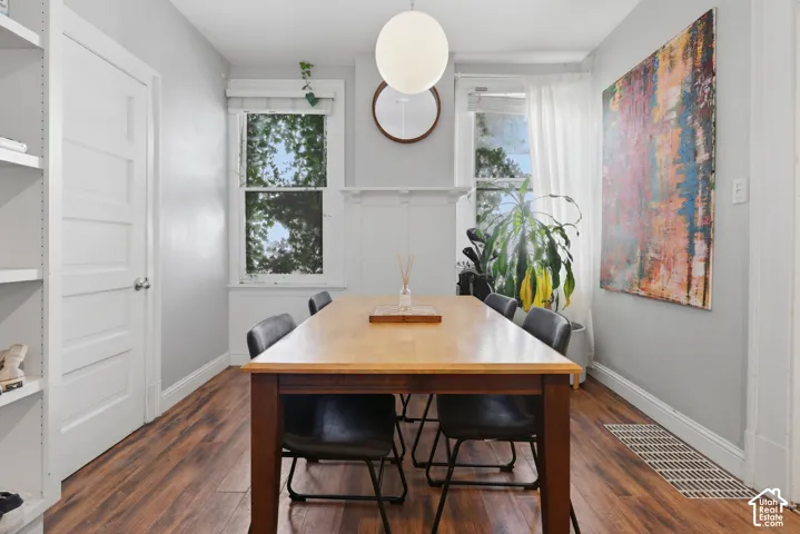 Wood-finish flooring, white built-in shelving, decorative fireplace mantel, globe pendant lighting, and oversized windows