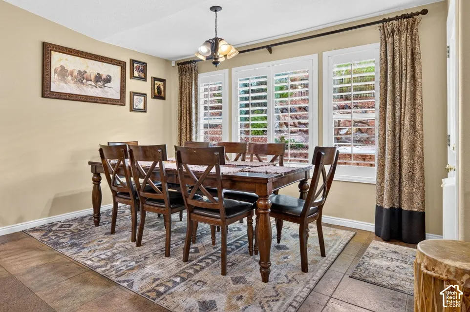 Dining area featuring tile flooring, plantation shutters, and a multi-light hanging fixture