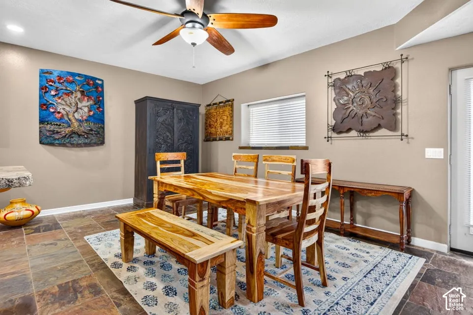 Multi-toned slate flooring, ceiling fan with wood-finished blades, and a single-panel glass-inset exterior door