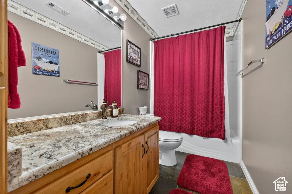 Bathroom featuring a stone-surface countertop, wood-finish cabinetry, an undermount sink, a full-width vanity mirror, and a tub-shower combination with a surround