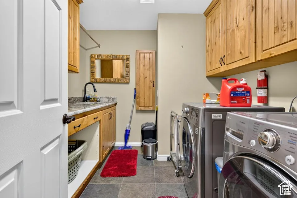 Laundry room featuring natural wood cabinetry, stone-finish countertop, undermount sink with matte black faucet, and tiled flooring