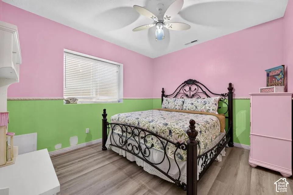 Wood-finish flooring, multi-paneled ceiling fan with integrated lighting, and horizontal slat window blinds