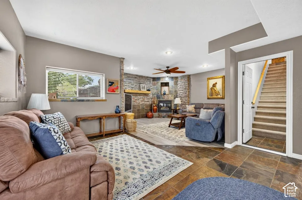 Corner fireplace featuring floor-to-ceiling stone surround, wood-finish mantel, and tiled hearth, complemented by large-format tile flooring and recessed lighting