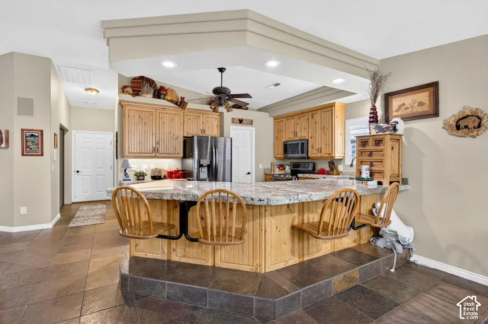 Kitchen featuring natural wood cabinetry, stone-finish countertops, recessed lighting, and tile flooring