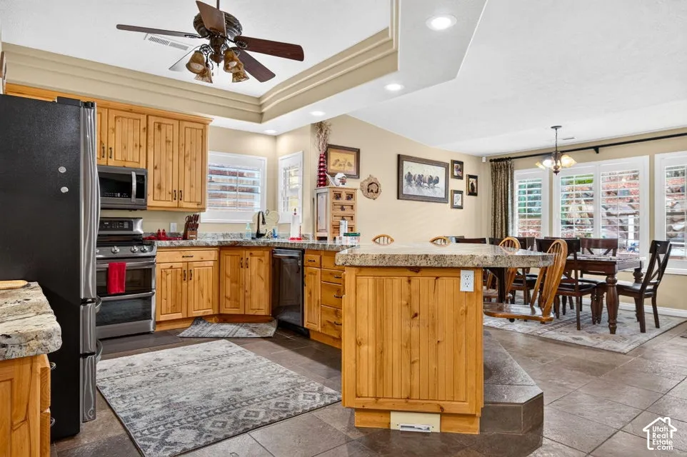 Kitchen featuring natural wood cabinetry, stone countertops, a central island, tile flooring, and recessed ceiling lighting