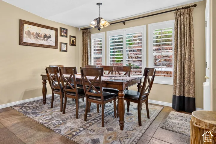 Dining area featuring tile flooring, plantation shutters, and a multi-light hanging fixture
