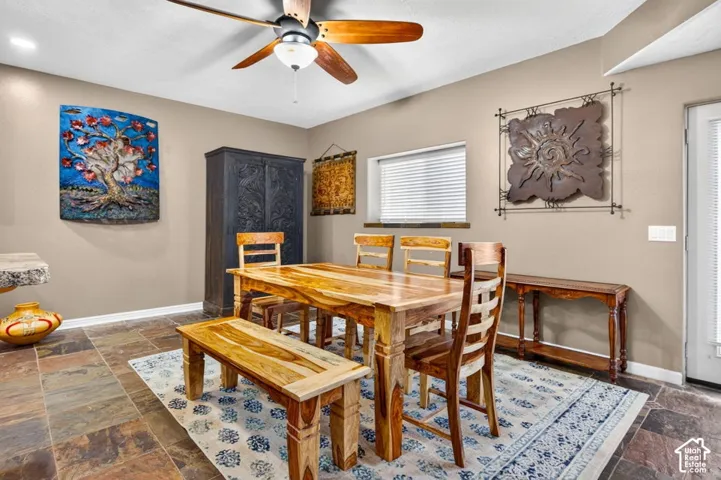 Multi-toned slate flooring, ceiling fan with wood-finished blades, and a single-panel glass-inset exterior door