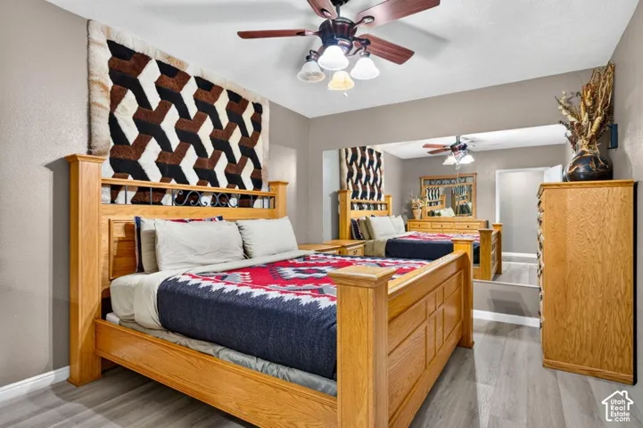 Large wall-mounted mirror, wood-finish flooring, and ceiling fan with integrated lighting