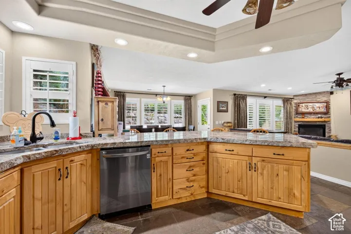 Kitchen featuring natural wood cabinetry, stone-surface countertops, tile flooring, recessed ceiling lighting, and a tiered tray ceiling