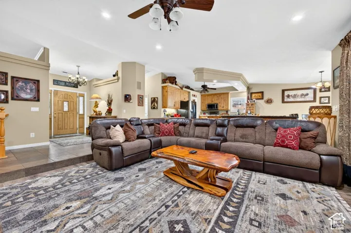 Open-concept interior featuring recessed lighting, ceiling fans with integrated lighting, wood-finish cabinetry, tile flooring, and a multi-panel wood front door