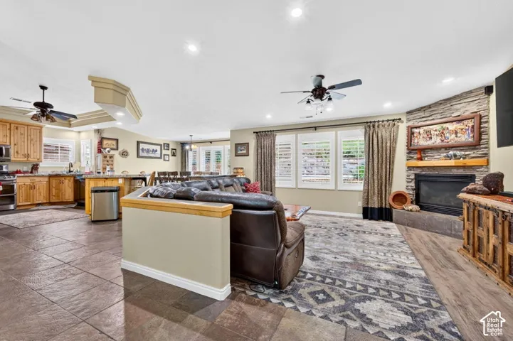 Open-concept interior featuring stone-surround fireplace with wood mantel, wood-finish flooring, tile flooring, and recessed ceiling lighting