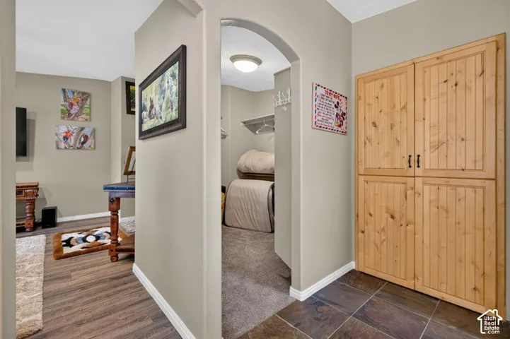 Arched entryway leading to a walk-in closet, wood-finish flooring, tile flooring, and floor-to-ceiling built-in natural wood cabinetry
