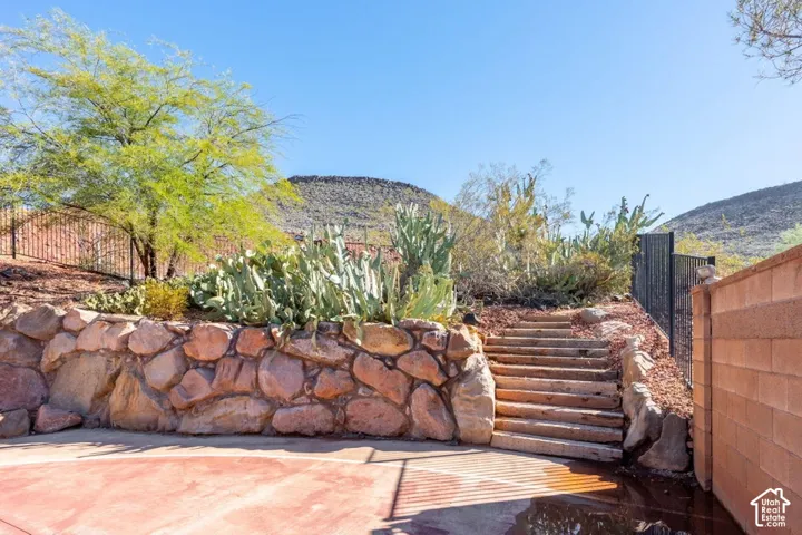 Terraced landscape featuring boulder retaining walls, stone stairs, and desert-inspired vegetation against a mountain backdrop
