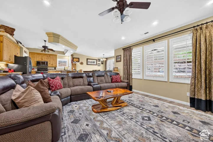 Open-concept interior featuring recessed lighting, ceiling fans, plantation shutter window coverings, and wood-finish cabinetry