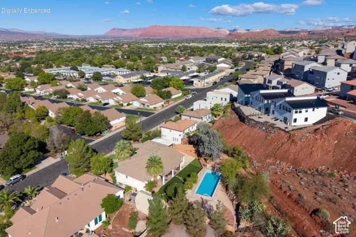 Aerial perspective featuring a private swimming pool, landscaped lawn, expansive desert terrain, and mountain backdrop
