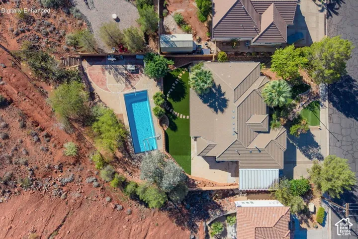 Aerial view featuring a rectangular swimming pool, integrated hardscaping, artificial turf lawn, and a covered rear patio