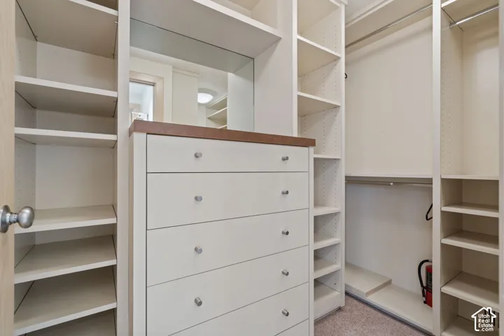 Custom built-in storage system featuring floor-to-ceiling shelving, integrated five-drawer dresser, inset mirror, and multiple clothing rods