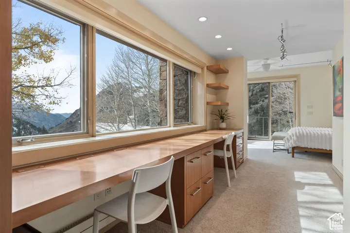 Built-in wood cabinetry with expansive desk surface, large windows, recessed lighting, and wall-mounted shelving