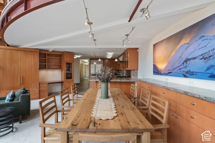Custom wood cabinetry featuring built-in storage and integrated desk space, stone-surfaced countertops, curved architectural ceiling detail, and multi-directional track lighting