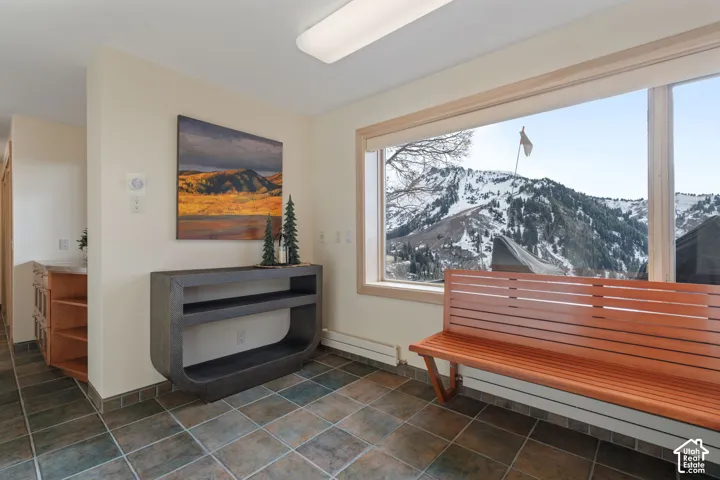 Large picture window with mountain backdrop, multi-tone tile flooring, and integrated wood-finish cabinetry