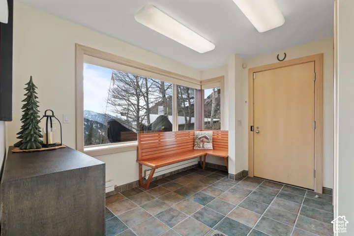 Entryway featuring multi-toned tile flooring, built-in wood slat bench seating, expansive windows with mountain scenery, and light-finished wooden door