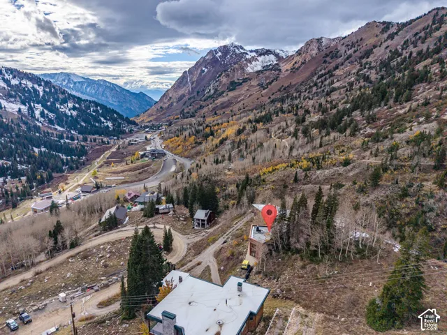 Aerial perspective featuring mountainous terrain with evergreen forest, native vegetation, and a paved road network