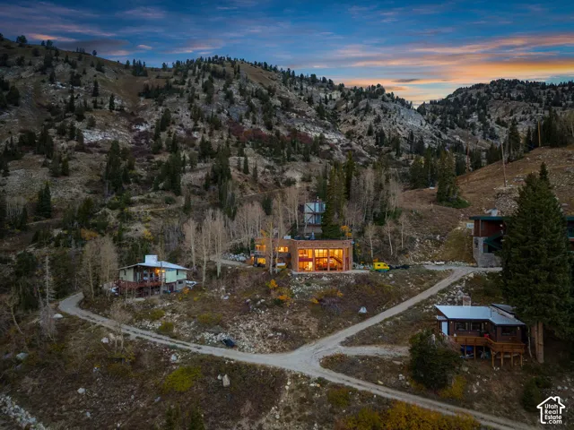 Multi-level residence featuring expansive floor-to-ceiling windows, stone exterior siding, tiered construction, and private hillside topography