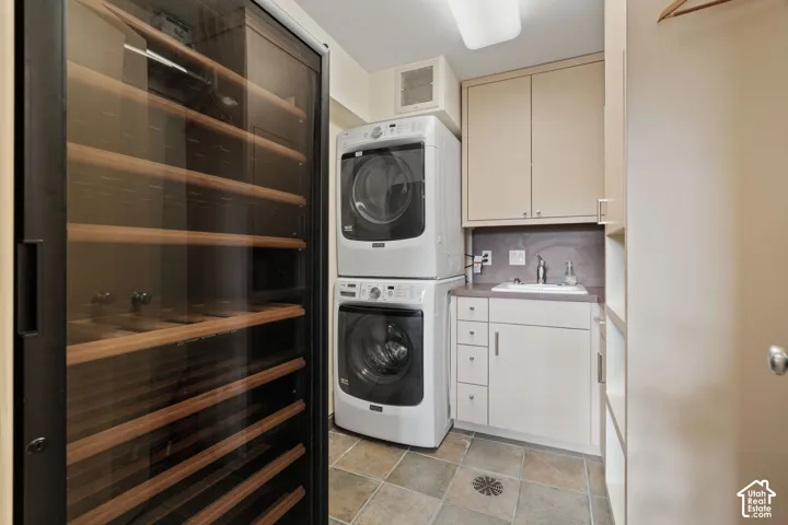 Built-in climate-controlled wine storage, stacked laundry appliances, integrated utility sink, solid-surface countertops, and cabinetry with tiered storage