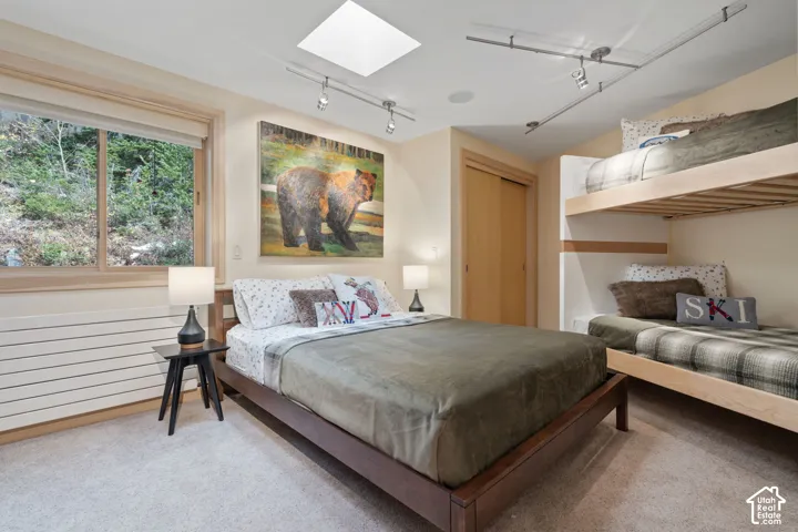 Bedroom featuring built-in wood bunk beds, a skylight, wood-trim sliding closet doors, and adjustable track lighting