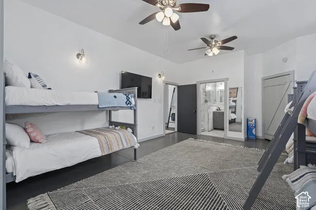 Room featuring dual ceiling fans with integrated lighting, wall-mounted sconces, and dark wood-finish flooring