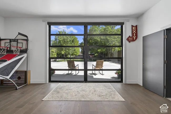 Full-light glass panel garage door, wood-finish flooring, white walls, and dark-toned door