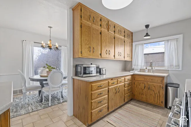 Warm wood cabinetry with abundant storage and drawer space, ceramic tile flooring, and stainless steel appliances create a functional kitchen layout