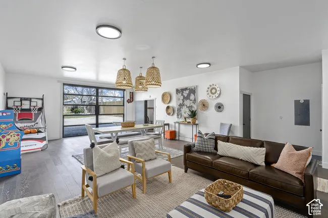 Open-concept living space featuring recessed ceiling lighting, large multi-pane windows with natural light, light wood-finish flooring, and woven pendant fixtures
