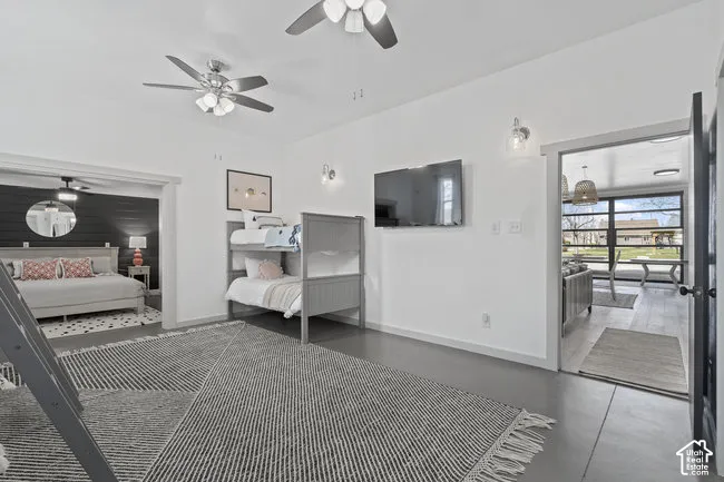 White walls with sconce lighting, two ceiling fans, and a mounted television