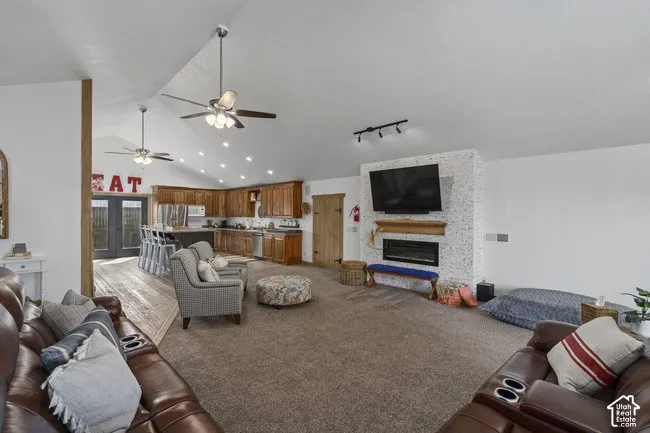 Vaulted ceilings with recessed lighting, integrated ceiling fans, wood-finish flooring, kitchen with wood cabinetry and island seating, and a fireplace feature wall