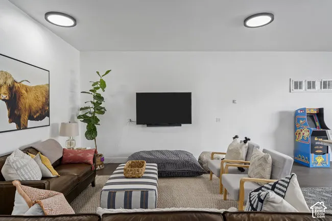 White walls with two flush-mount ceiling lights, an entertainment wall with a mounted television, and a recessed arcade game