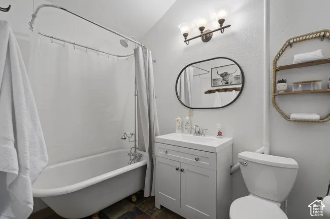 Freestanding clawfoot tub with shower fixture, single vanity with integrated sink, wall-mounted light fixture, and oval framed mirror