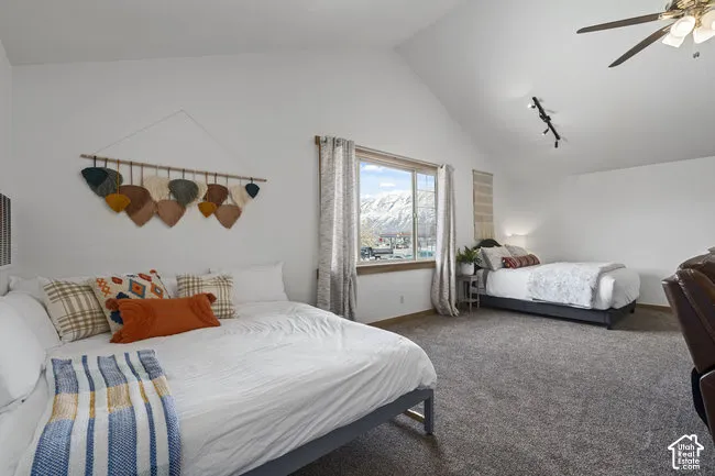 Bright, light-filled bedroom suite featuring vaulted ceilings, carpeted flooring, and abundant natural light from multiple windows framing mountain scenery