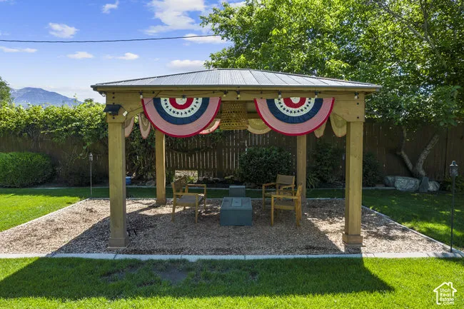 Spacious covered pavilion with wood beam construction and metal roof, anchored on a gravel base and surrounded by mature landscaping